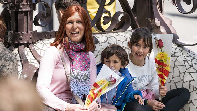 Una familia con niños muestran las rosas de Sant Jordi sentados en el paseo de Gràcia