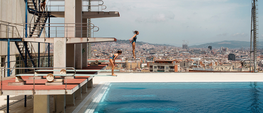 Two girls jumping off a trampoline in the Picornell swimming pools. 