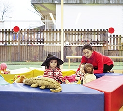Group of children playing with soft toys and an adult woman