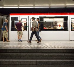 Estació de metro amb el tren aturat i persones a l’andana