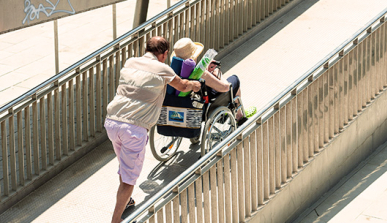 Man pushing a wheelchair along an access ramp to the beach 